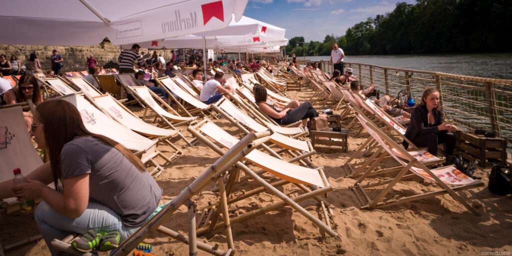 Zahlreiche Liegestühle und Sonnenschirme am Würzburger Stadtstrand, ideal zum Sonnenbaden und Entspannen – das ultimative Strandgefühl in Würzburg.