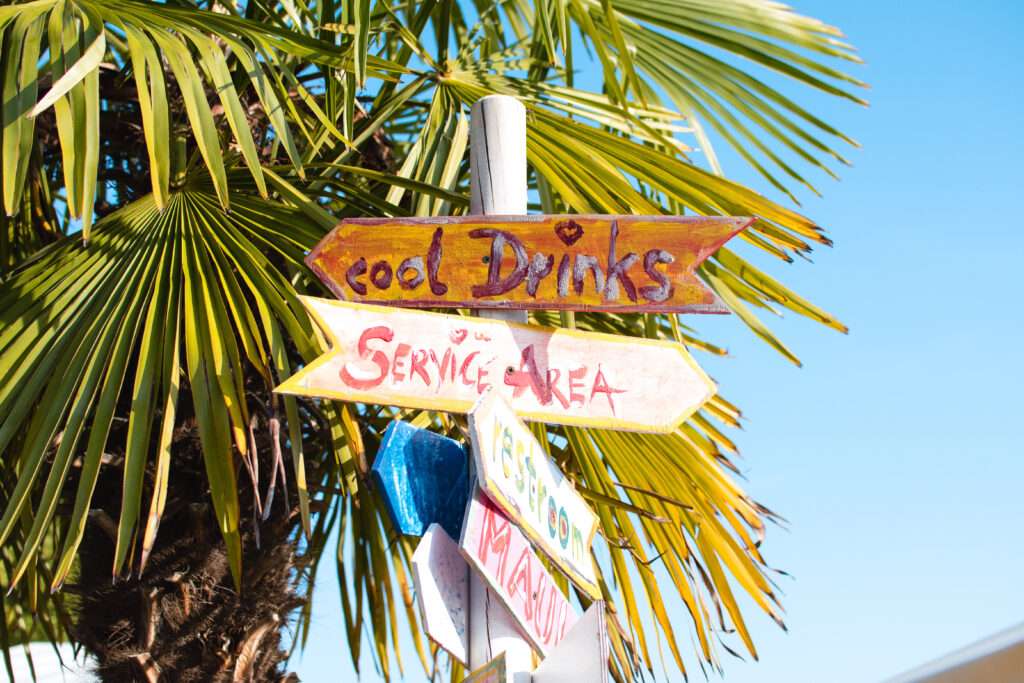 in bunter Wegweiser am Würzburger Stadtstrand, der zu "FOOD DRINKS" und "Social Area" zeigt – Orientierung und Spaß am Main.