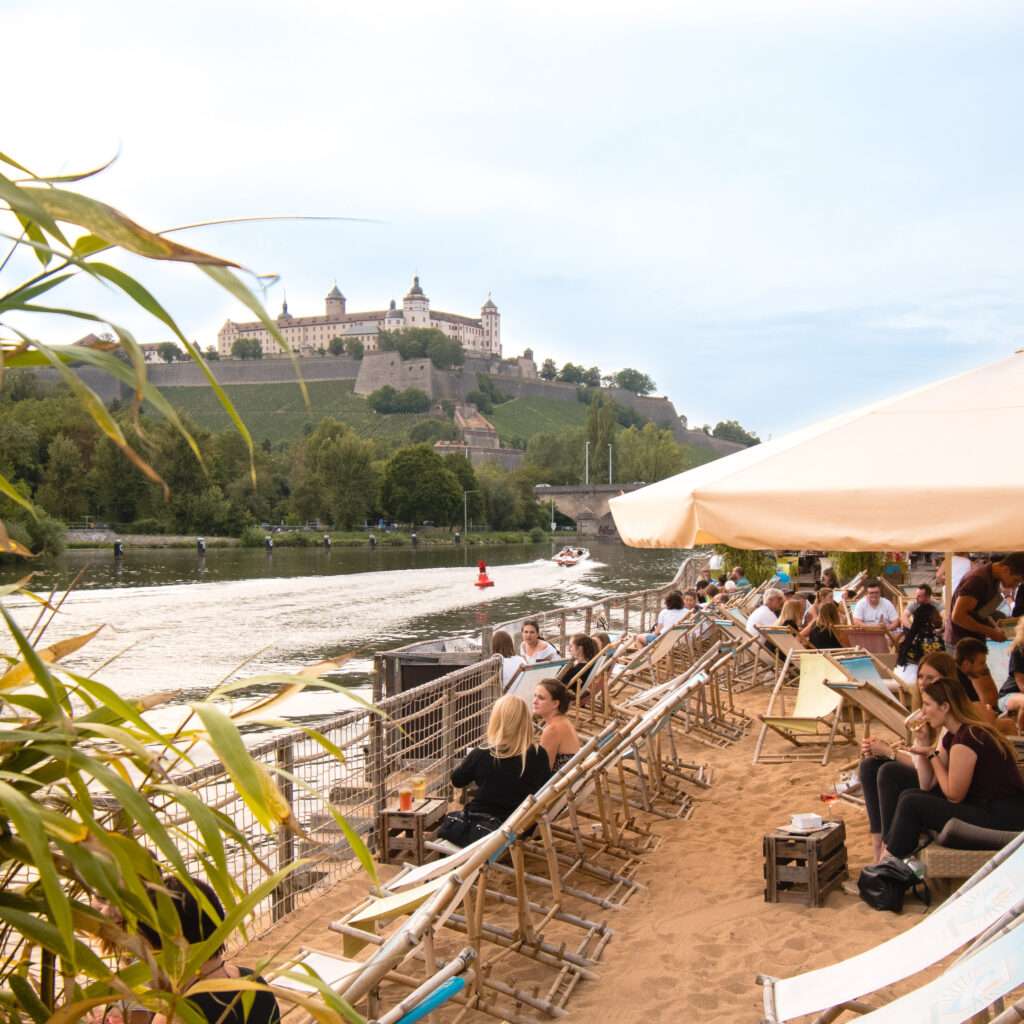 Komfortable Liegeflächen und Sonnendecks am Würzburger Stadtstrand, ideal zum Entspannen direkt am Main mit Blick auf die Festung Marienberg