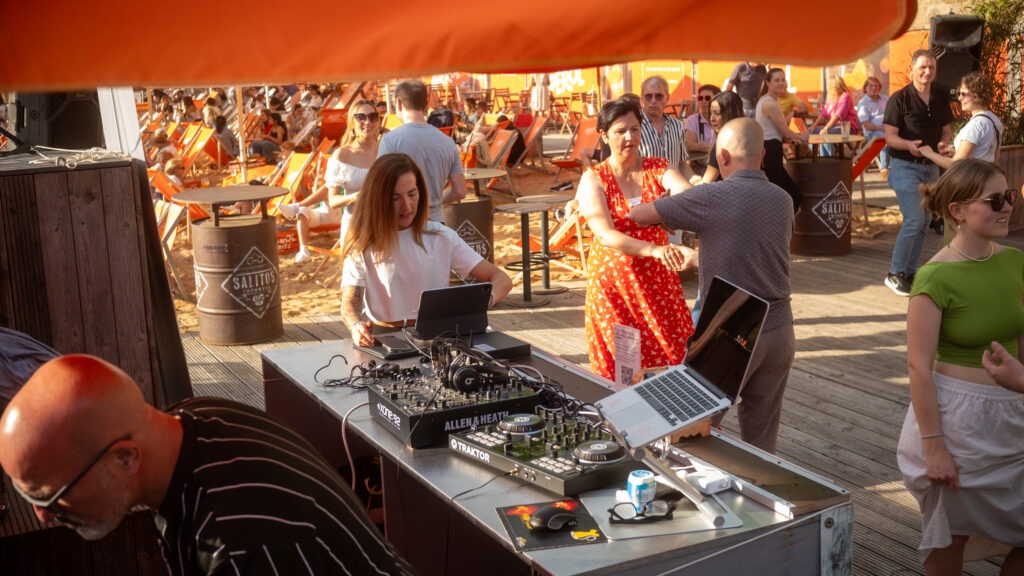 Gäste tanzen bei Live-DJ-Musik auf dem Stadtstrand Würzburg bei sommerlichem Wetter und Sand unter den Füßen