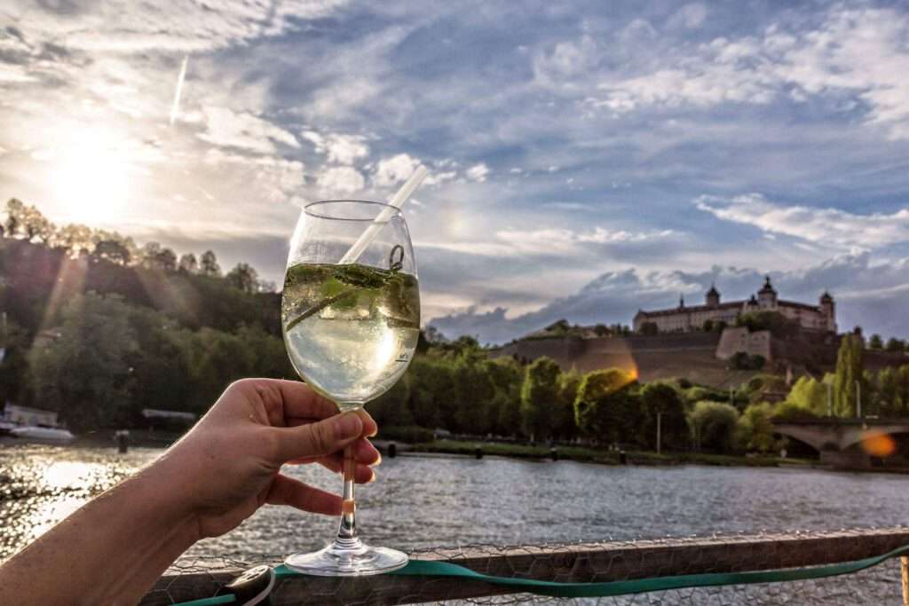 Ein Glas Wein am Würzburger Stadtstrand mit Blick auf den Main und die Festung Marienberg – perfekter Abendausklang.